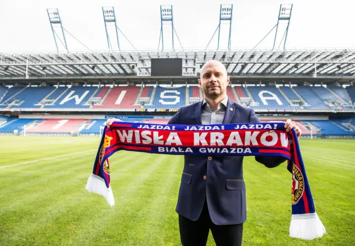 Artur Skowronek z szalikiem Wisły Kraków na tle stadionu. "Jazda! Wisła Kraków! Biała Gwiazda!" - krzyczy kibic.