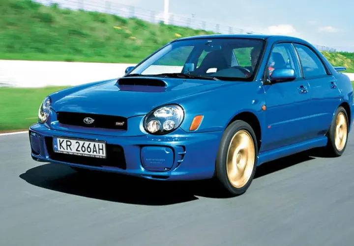 Niebieskie, małe szybkie auto Subaru Impreza WRX STI pędzi po torze wyścigowym.