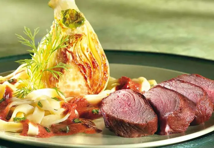 Tranches de rumsteak d'agneau rosé, accompagnées de pâtes fraîches, d'une sauce rouge et d'un fenouil braisé.