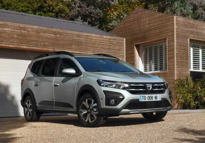 Dacia Jogger grigio metallizzato, un'auto che consuma meno GPL, parcheggiata davanti a una casa moderna in legno.
