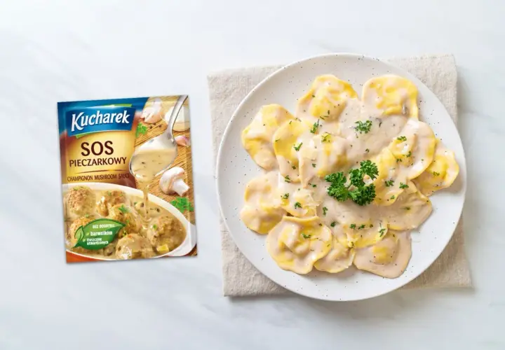 Ravioli polane kremowym sosem pieczarkowym, obok opakowanie sosu Kucharek.