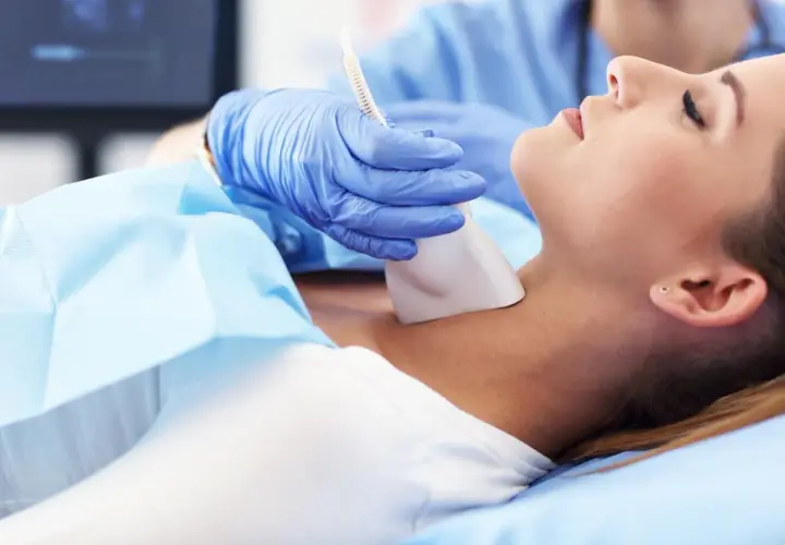 Lekarz wykonuje badanie USG tarczycy, które jest formą diagnostyki obrazowej. Pacjentka leży spokojnie podczas procedury.