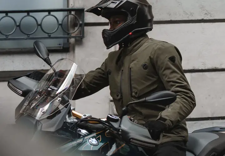 Motociclista con casco y chaqueta de aventura, que es Gore-Tex, lista para el viaje.