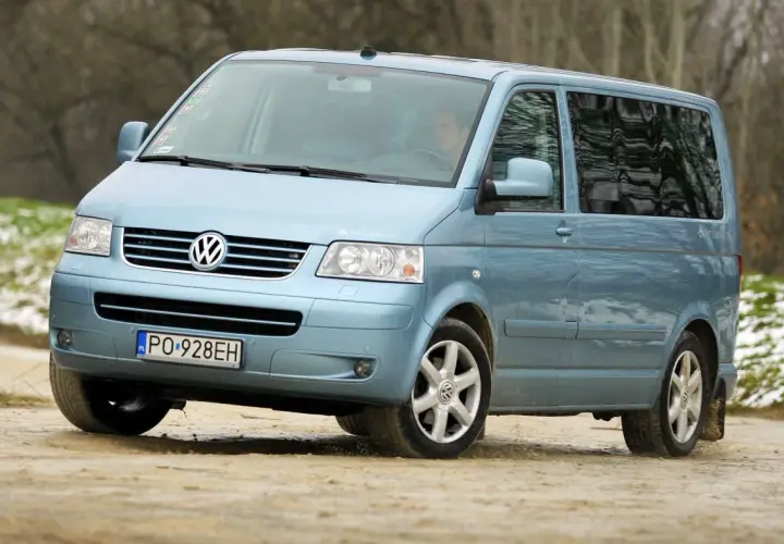 Jasnoniebieski Volkswagen Transporter T5 na drodze gruntowej.