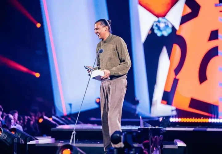 Stromae z nagrodą na scenie, jakby śpiewał "Papaoutai tekst po polsku".