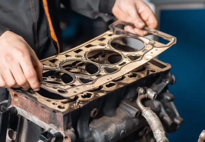 Meccanico posiziona una nuova guarnizione della testata su un motore. Scopri quanto costa cambiare la guarnizione della testata.