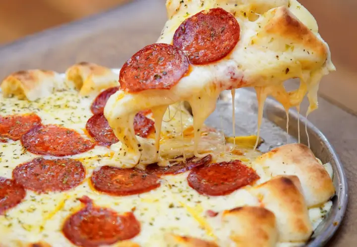 Pizza de pepperoni con queso mozzarella derretido y estirándose.