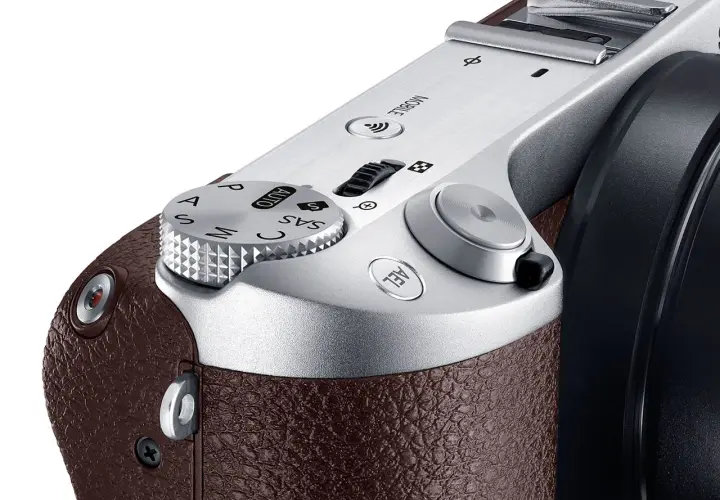 Zbliżenie na górną część eleganckiej, brązowej obudowy aparatu samsung lustrzanka cyfrowa. Widoczny pokrętło trybów i przyciski.
