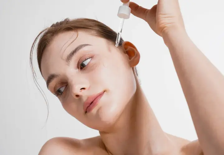 Delikatna skóra kobiety otrzymuje kroplę serum. Zobacz, co daje serum do twarzy dla promiennej cery.