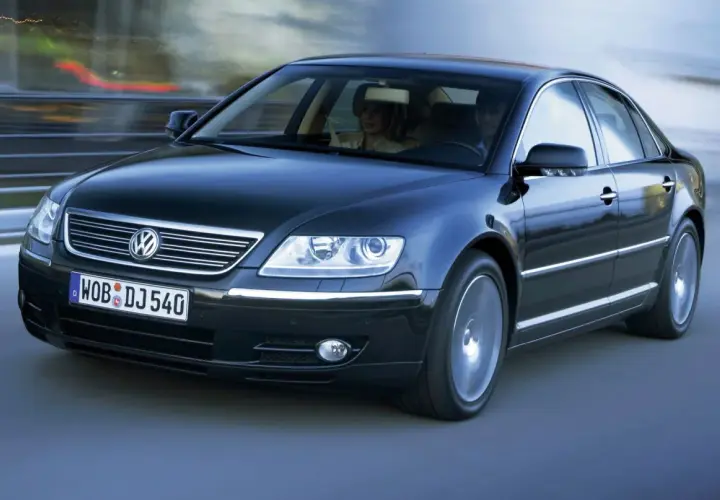Elegancki, czarny Volkswagen Phaeton w ruchu, z parą pasażerów w środku.