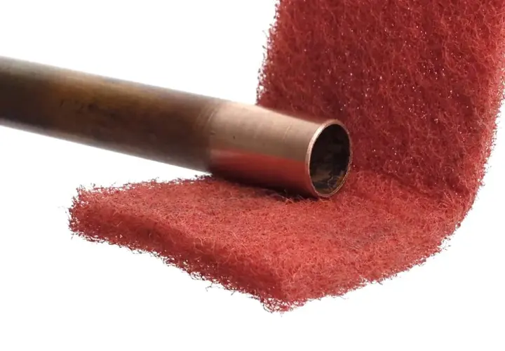 Miedziana rura przygotowana do lutowania aluminium z miedzią, na czerwonej druciance.