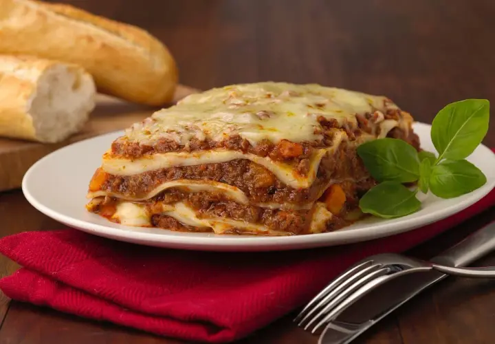 Herzhafte Lasagne mit Hackfleisch und Käse, dazu Baguette. Welcher Wein zu Lasagne passt, ist eine Frage des Geschmacks, aber ein kräftiger Rotwein ist oft ideal.