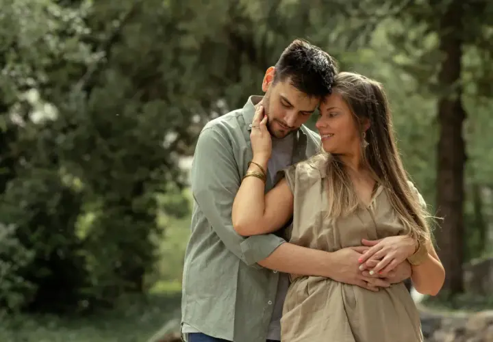 Coppia abbracciata in un parco, un momento di tenerezza che racchiude il vero amore significato.