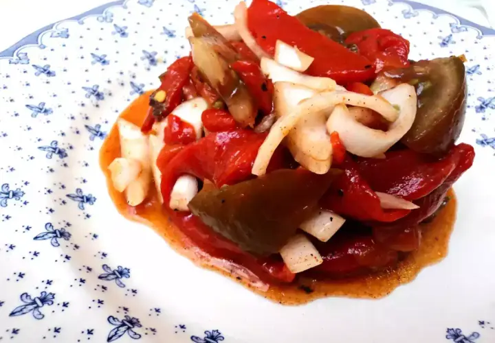 Deliciosa ensalada de pimientos asados con cebolla, bañada en un aderezo rojizo. Un plato lleno de sabor y color.