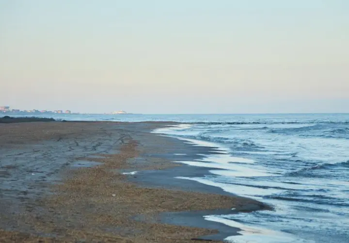Plaża nad morzem Kaspijskim, które wysycha. W oddali widać zabudowania.