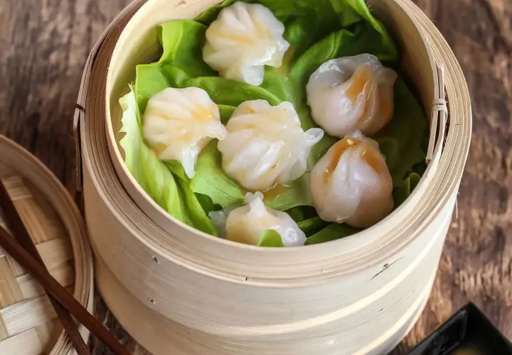 Délicieux ravioli crevette italien, cuits à la vapeur dans un panier en bambou, servis sur des feuilles de laitue.