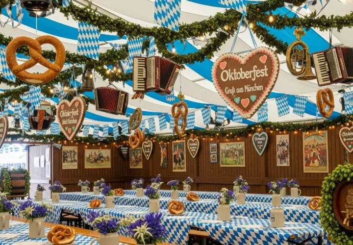 Wystrój namiotu Oktoberfest: obrusy w kratę, precle, akordeony, serca z piernika i dekoracje.