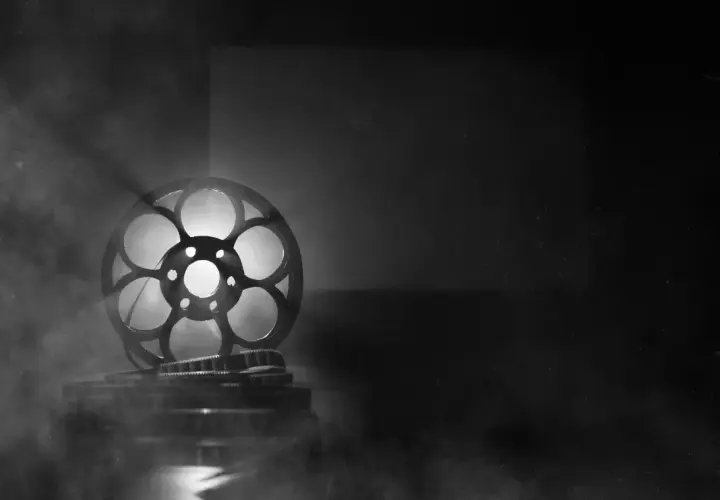 Stara taśma filmowa mk2, oświetlona od tyłu, unosi się w dymie, tworząc magiczną atmosferę kina.