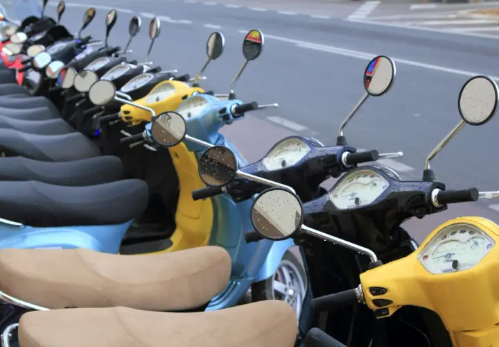 Línea de motos y scooters de colores aparcadas en la calle. Para saber si una moto está libre de cargas, revisa su documentación.