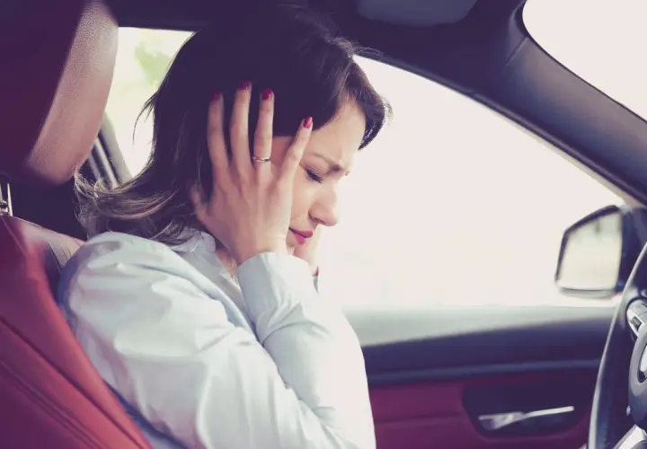 Donna in auto si tappa le orecchie per il fastidioso cigolio macchina.