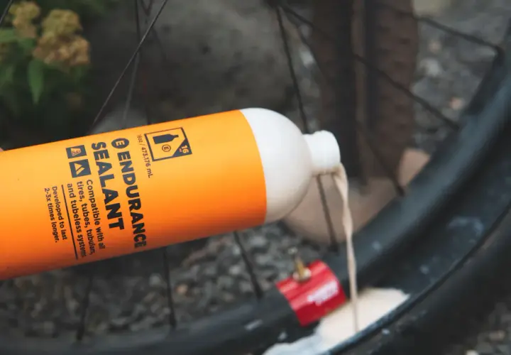Pouring orange Endurance Sealant into a bike tire. This sealant is designed for longer-lasting protection compared to regular options.
