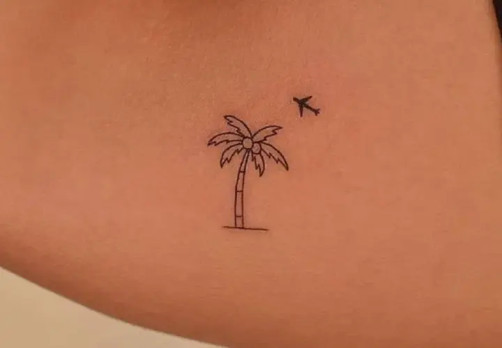 Minimalistyczny tatuaż palma z kokosami i lecącym samolotem. Symbol podróży i wakacji.