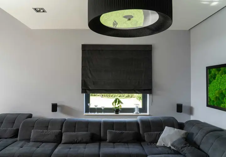 Elegancka roleta rzymska do salonu, wykonana z ciemnego materiału, tworzy przytulną atmosferę.
