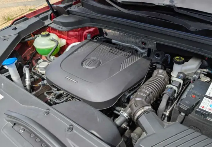 Motor de coche con cubierta negra, batería y depósito de refrigerante verde. ¿Cuántos caballos tiene un coche normal?