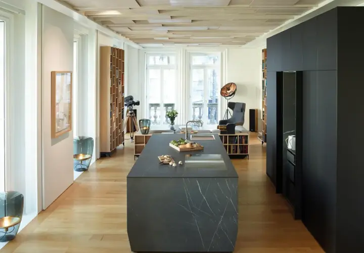 Cucina moderna con isola in pietra, parquet chiaro e dettagli in cementine.