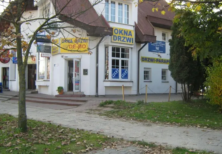 Budynek z żółtymi banerami "OKNA DRZWI" i "DRZWI PARAPETY" w Olsztynie.