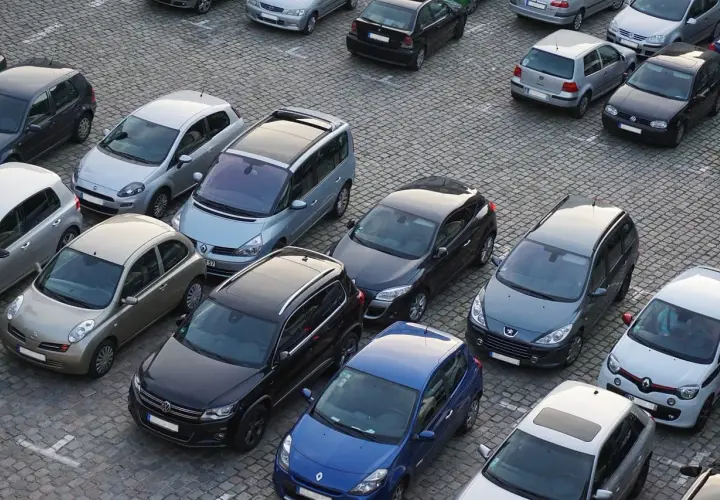 Parking tylko dla mieszkańców, mandat grozi za parkowanie. Wiele samochodów na brukowanym placu.
