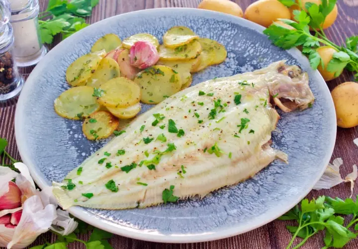 Delicioso lenguado al horno con patatas panadera y ajo. Un plato principal ligero y sabroso.