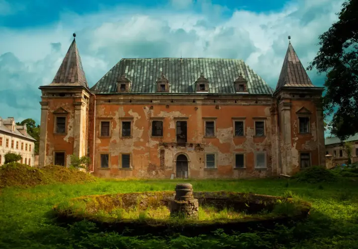 Zrujnowany pałac z wieżyczkami, porośnięty mchem i otoczony bujną zielenią. Kruszyna historii w zapomnianym miejscu.