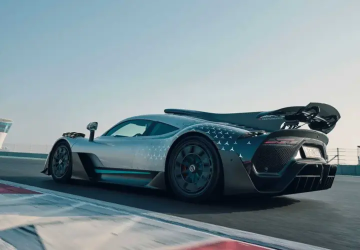 Srebrny Mercedes-AMG ONE z charakterystycznym wzorem gwiazdek na karoserii pędzi po torze wyścigowym.