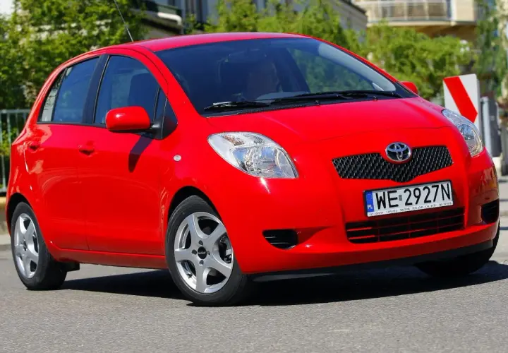 Czerwony Toyota Yaris 2009 z polskimi tablicami WE 2927N jedzie po ulicy.