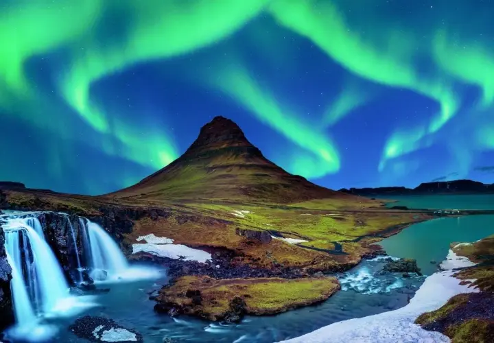 Góra Kirkjufell i wodospad pod zorzą polarną na Islandii.