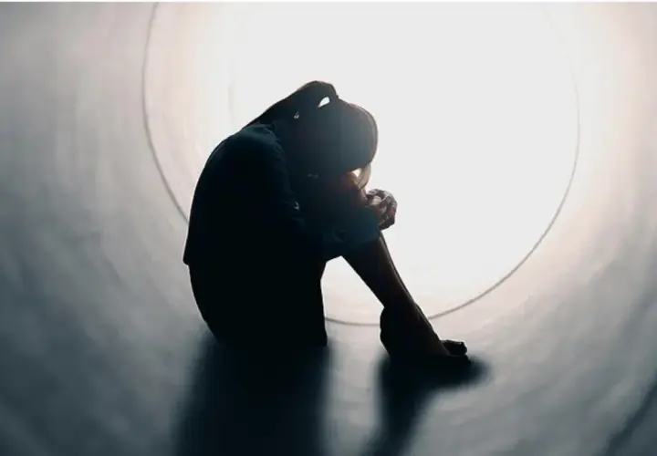 Silhouette di una persona rannicchiata in un tunnel, simbolo di solitudine e mancanza di affetto.