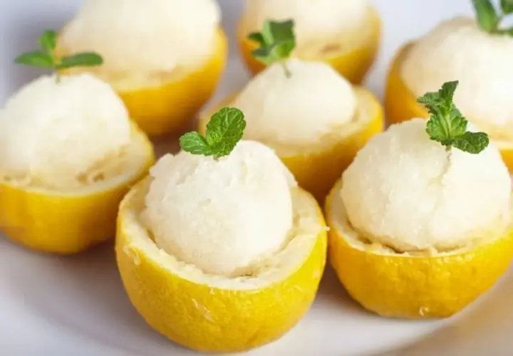 Sorbet cytrynowy w połówkach cytryn, udekorowany listkami mięty.