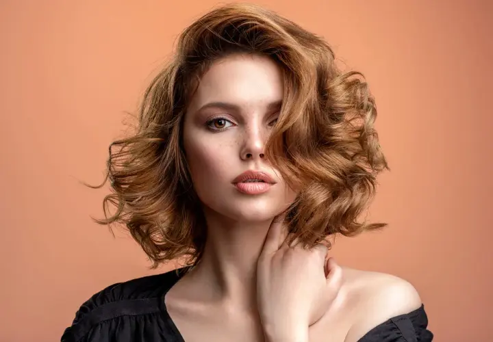 Mujer con pelo ondulado color cobre, un estilo que marca la tendencia pelo 2026.