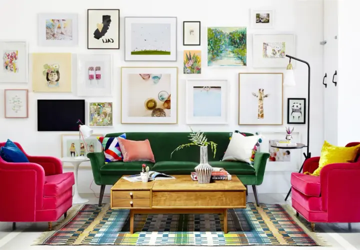 Salon w stylu new eklektyzm: zielona sofa, fuksjowe fotele, kolorowy dywan i ściana pełna różnorodnych obrazów.