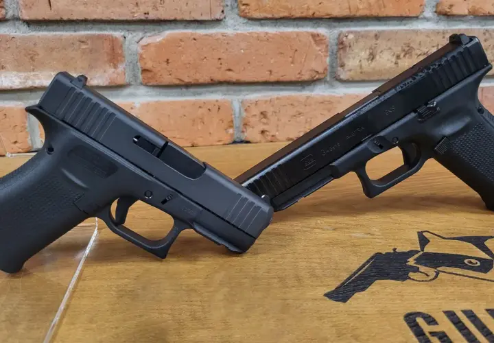 Dwa pistolety Glock, jeden na drugim, na drewnianym blacie z ceglanym tłem. Jeden z nich to pistolet czarnoprochowy Glock.