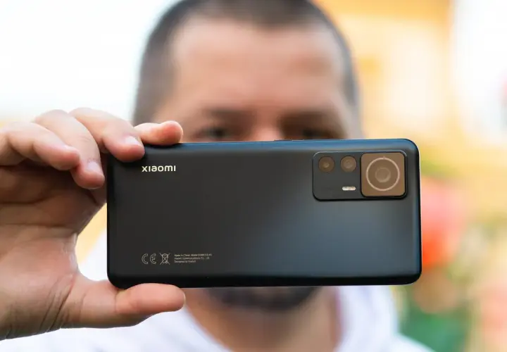 Dłoń trzyma czarny smartfon Xiaomi z widocznym modułem aparatów.