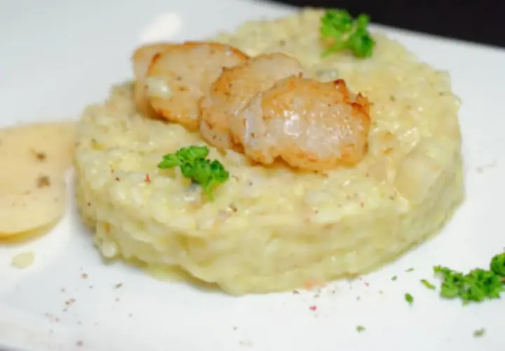 Un crémeux risotto poire gorgonzola, garni de Saint-Jacques poêlées et d'une touche de persil frais.