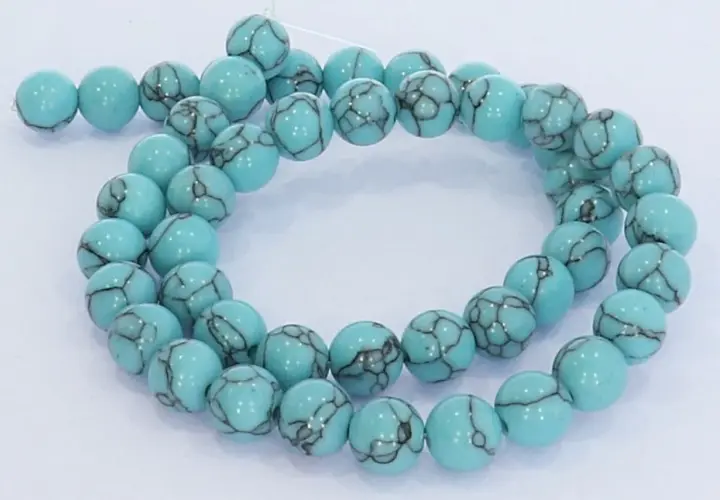 Eine Kette aus hellblauen, runden Perlen mit dunklen Äderungen, die an den Himmel erinnern. Der türkis schimmert in der Sonne.