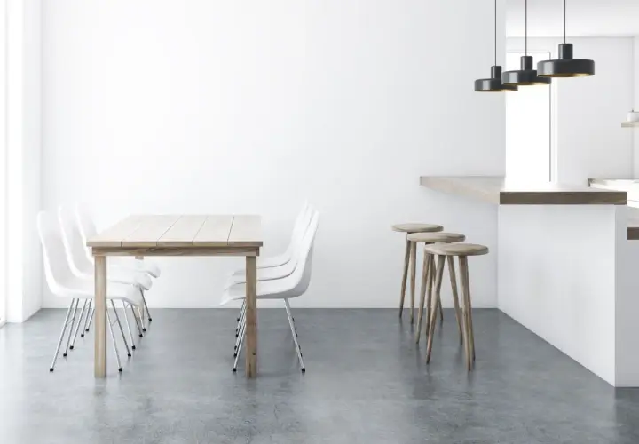 Tavolo in legno con sedie bianche e sgabelli al bancone, su un elegante **pavimento senza fughe**.