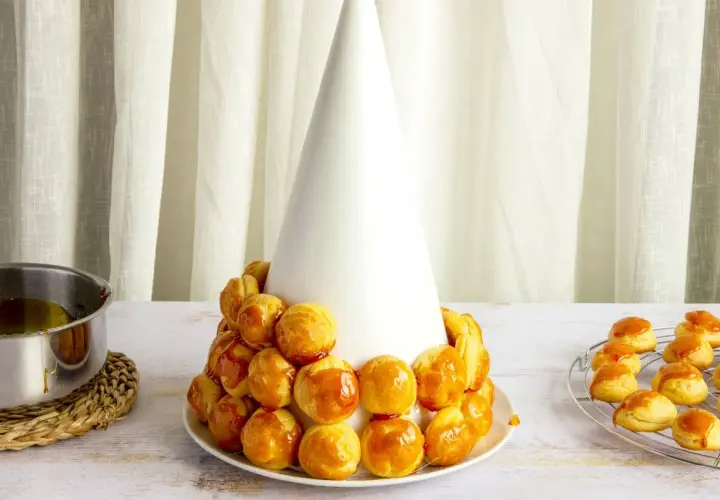 Tarta de profiteroles en proceso, con los pastelitos dorados y brillantes, listos para ser cubiertos de caramelo.