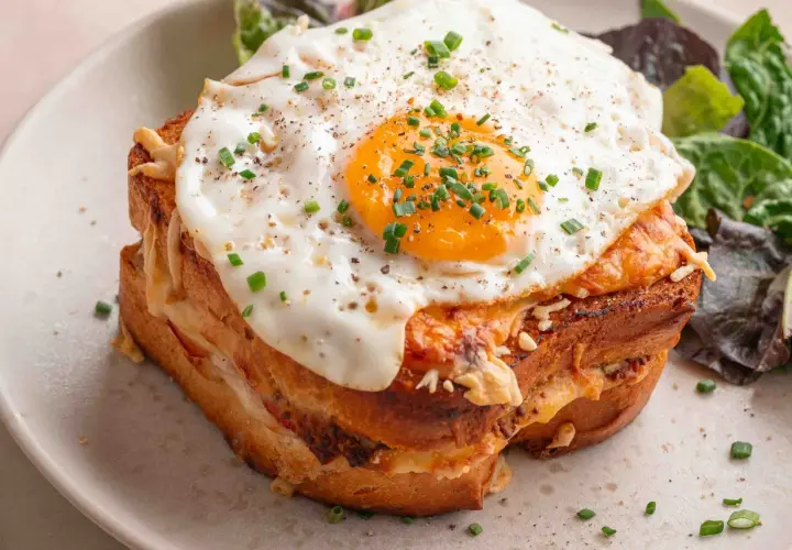 Un délicieux croque madame recette, avec un œuf au plat coulant, du fromage fondant et une salade verte. Un plat gourmand à souhait.