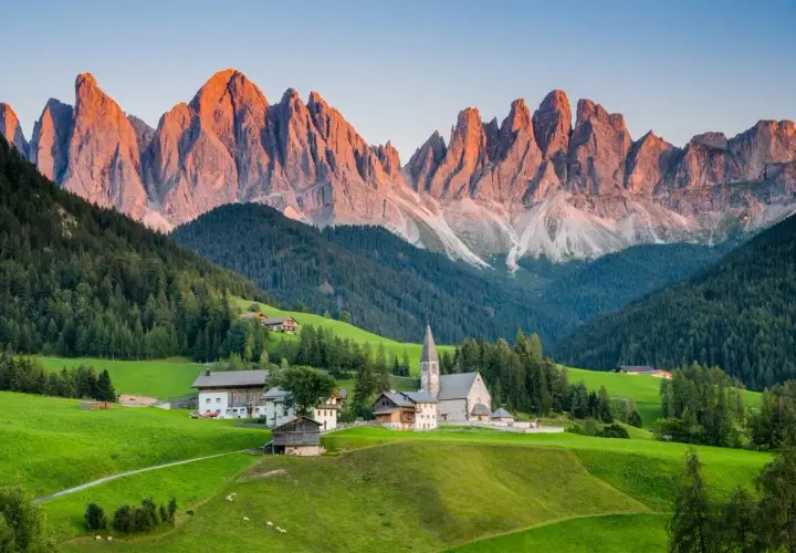 A picturesque village nestled in a valley, with the jagged peaks of the Dolomites catching the golden light, a stark contrast to the gentler slopes of the Alps.