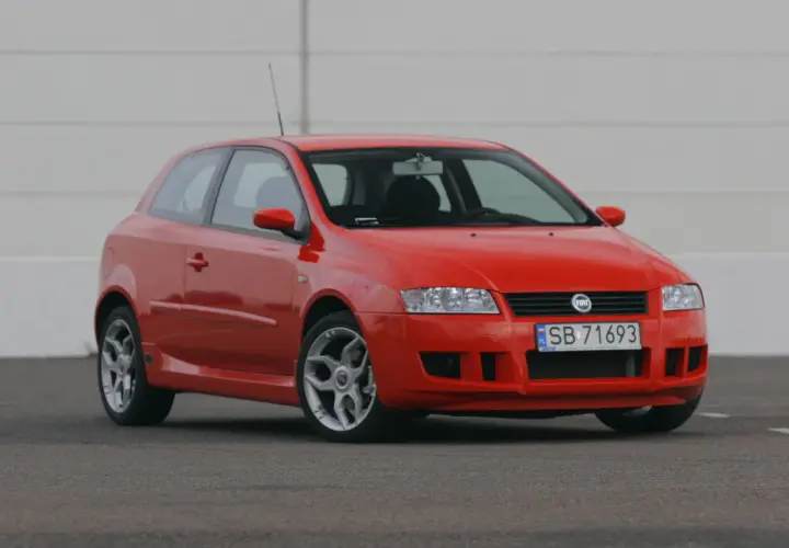 Czerwony Fiat Stilo 1.9 JTD na tle białej ściany, gotowy do jazdy.