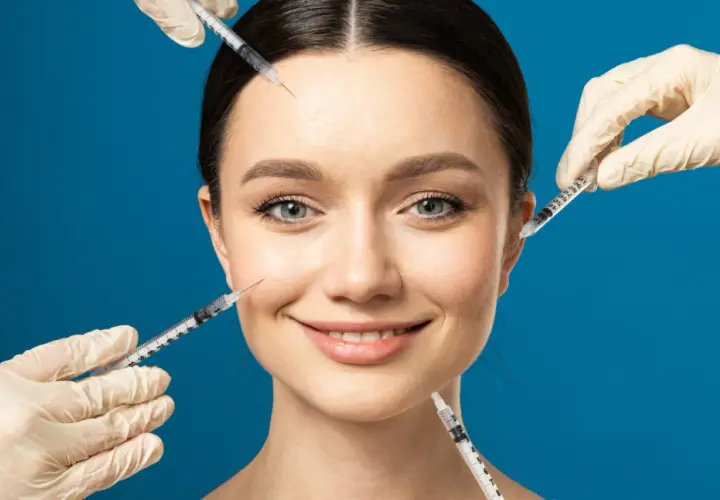 Ansiktsbehandling med botox och fillers. En kvinna ler medan flera sprutor närmar sig hennes ansikte för injektioner.